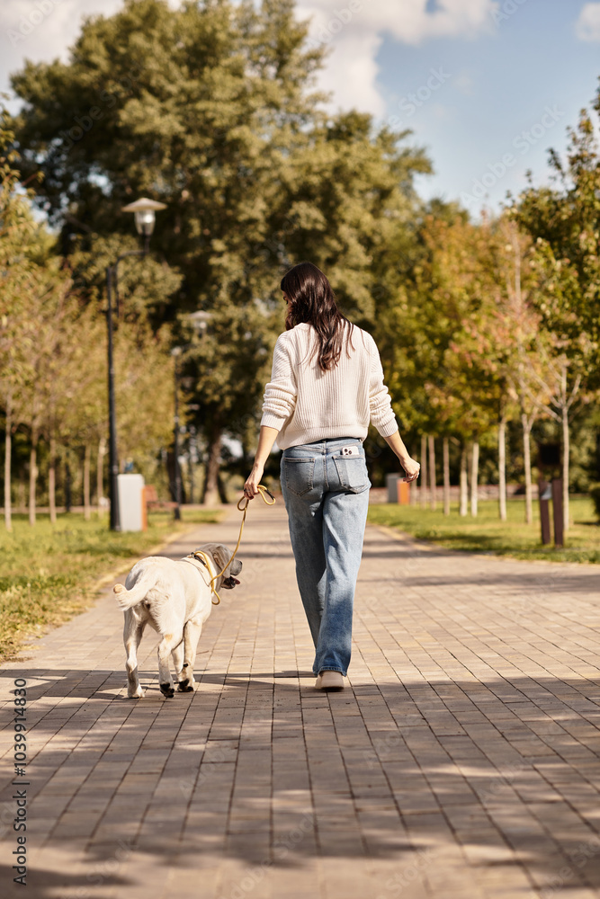A beautiful woman dressed in cozy autumn attire strolls through a park with her dog. A beautiful woman dressed in cozy autumn attire strolls through a park with her dog.