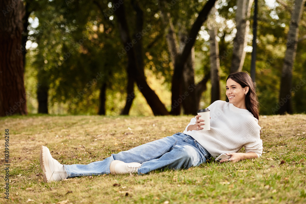 A young woman lounges in the park, sipping a warm drink while surrounded by autumn foliage. A young woman lounges in the park, sipping a warm drink while surrounded by autumn foliage.