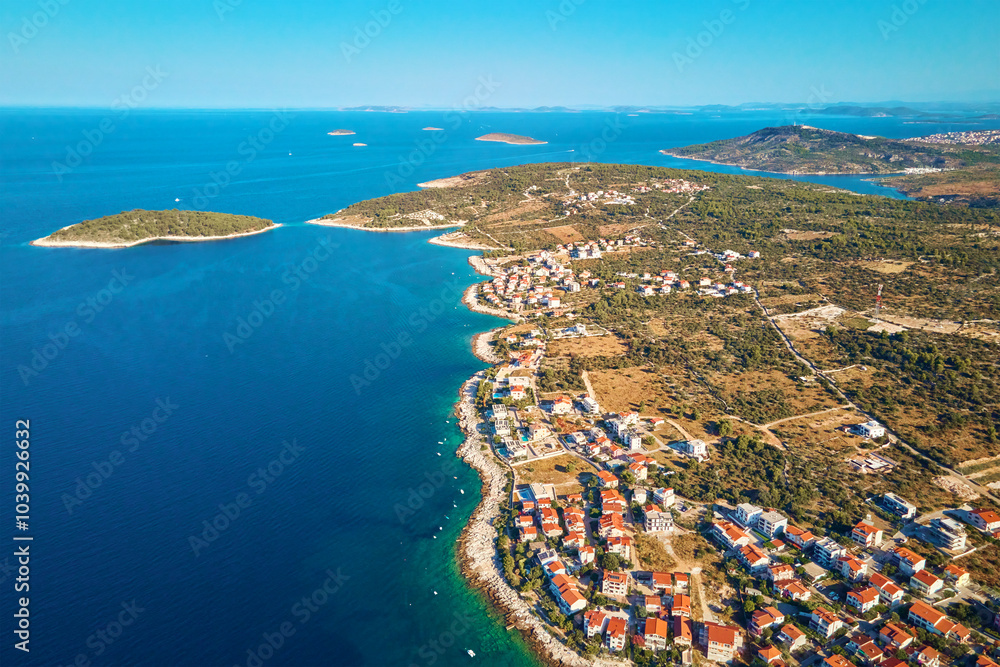 Fototapeta premium Aerial view of Adriatic sea coastline with coastal village and boats along shoreline. Panorama of tourist town Rogoznica in Croatia on Adriatic Sea. Summer travel concept