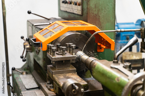 Cuadro en lienzo A close up of a lathe machine with an orange safety guard, machine is cutting a piece of metal