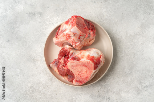 Raw beef bones for making broth in a white plate on a culinary kitchen table top view with a copyspace