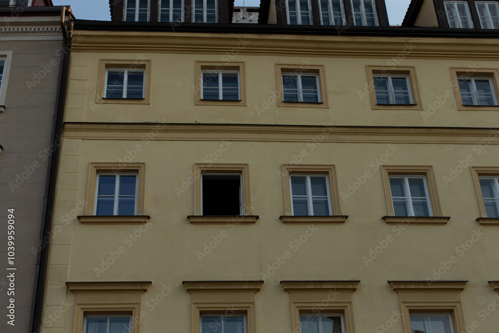 A detailed view of a historic building's facade featuring an open window amidst a classic architectural design. A detailed view of a historic building's facade featuring an open window amidst a classic architectural design.