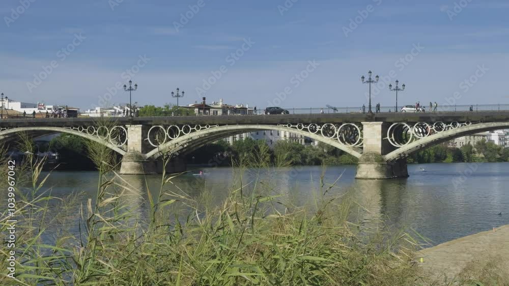 personas y coches pasando por encima del puente de Triana que divide las dos orillas por encima del rio guadalquivir personas y coches pasando por encima del puente de Triana que divide las dos orillas por encima del rio guadalquivir