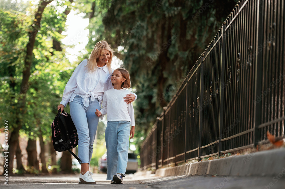Schoolgirl with her mother are outdoors together Schoolgirl with her mother are outdoors together