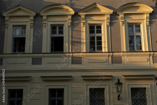 An elegantly designed facade showcases classic windows and intricate details, softly illuminated by gentle light