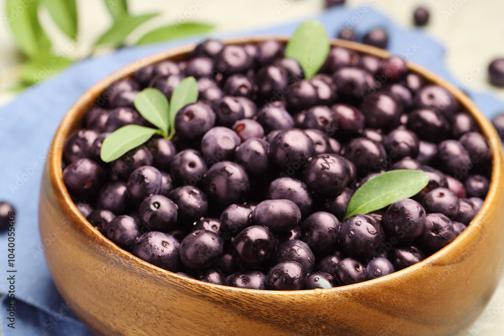 Ripe acai berries and leaves in bowl on table, closeup Ripe acai berries and leaves in bowl on table, closeup