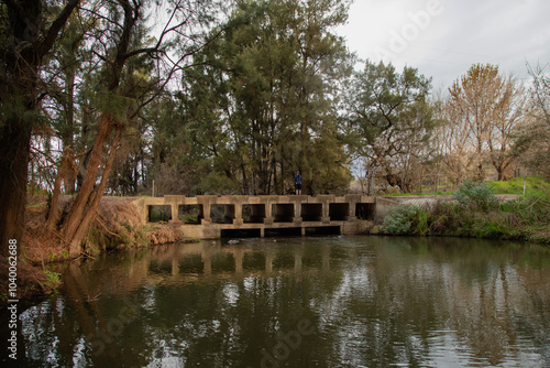 Teen boy walking across low bridge over the Cudgegong River in rural New South Wales photo