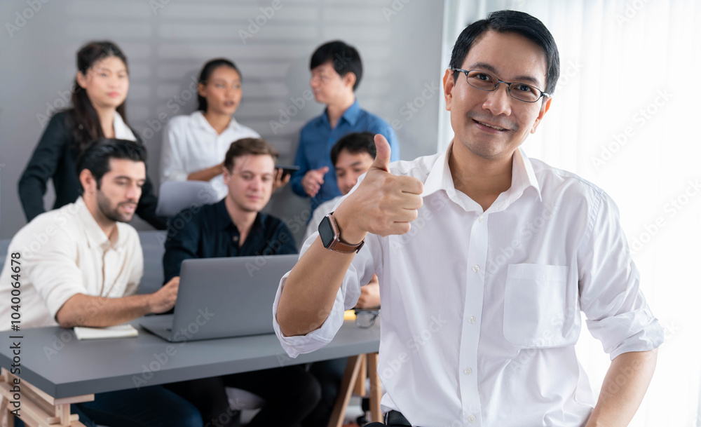 Obraz premium Confidence and happy smiling businessman portrait with background of his colleague and business team working in office. Office worker teamwork and positive workplace concept. Prudent