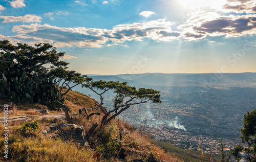 Scenic view of Lubango Angola highlighting the sun casting rays over the city at dusk with distant hills in the background photo