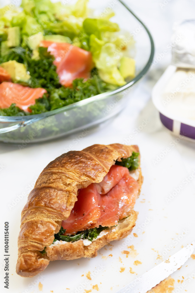 Delicious croissant filled with smoked salmon and greens, served with a side of salad for a healthy meal. Delicious croissant filled with smoked salmon and greens, served with a side of salad for a healthy meal.