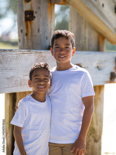 Two indigenous boys standing next to a timber house frame photo