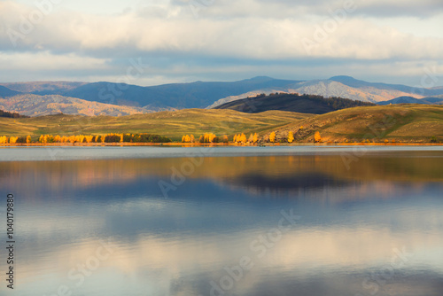 Lake in the autumn mountains. Yellow trees and mountains are reflected in the lake at sunrise. photo