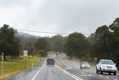 cars driving on road in rain with windscreen wipers going photo