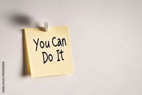 A soft-lit sticky note attached with a clip bears the motivational phrase 'You Can Do It', encouraging perseverance and success. Ideal for daily inspiration. photo