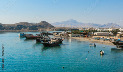 Traditional fishing boats anchored in Sur Oman on a sunny day with mountains in the background