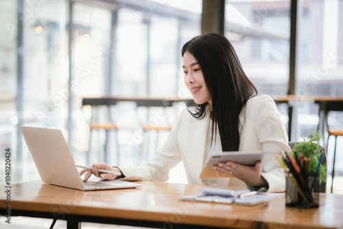 Beautiful Asian businesswoman focused on reviewing documents in a modern office.