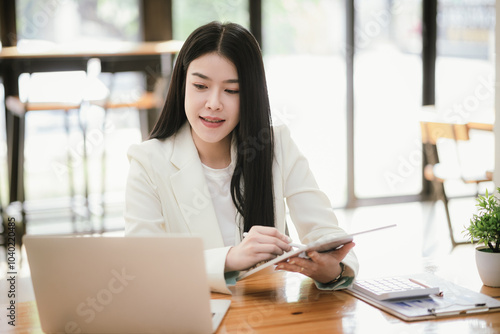 Beautiful Asian businesswoman focused on reviewing documents in a modern office.