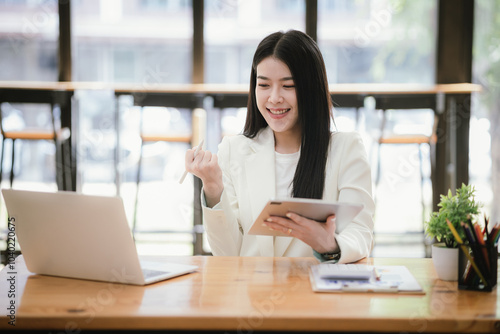 Beautiful Asian businesswoman focused on reviewing documents in a modern office.