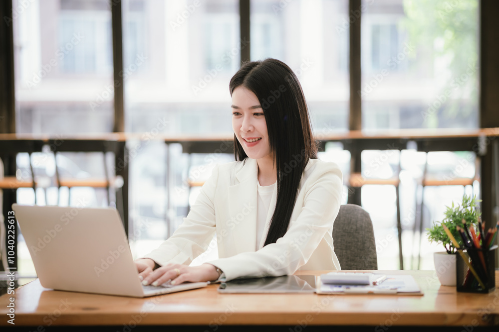 Portrait of a young businesswoman working on a laptop in an office Portrait of a young businesswoman working on a laptop in an office
