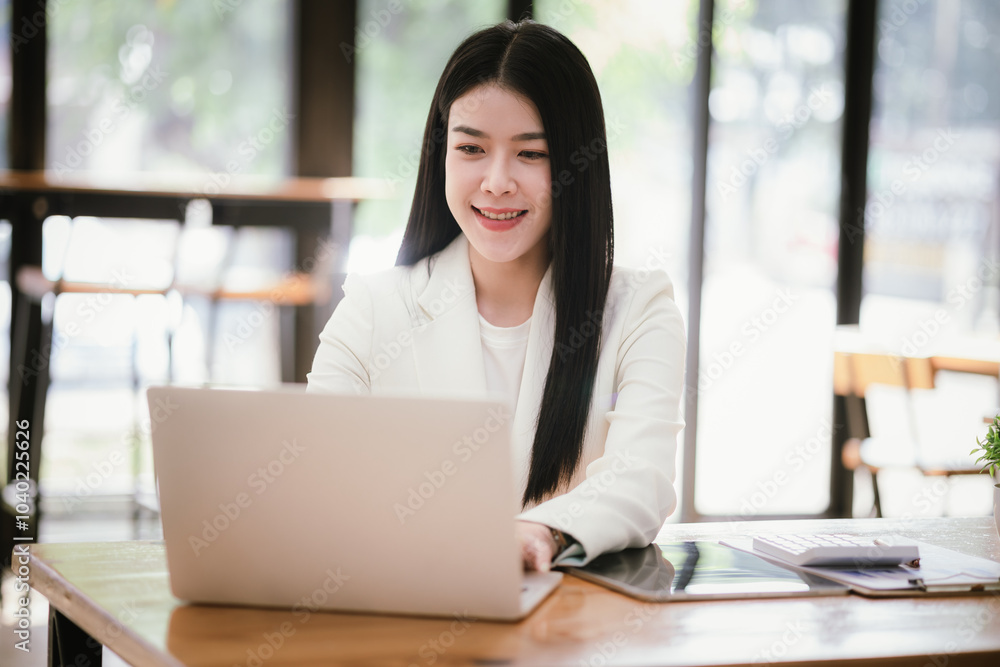 Portrait of a young businesswoman working on a laptop in an office Portrait of a young businesswoman working on a laptop in an office