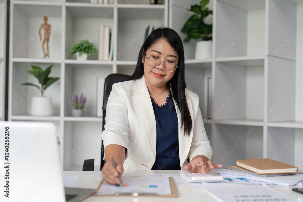 Middle Aged Business Woman Working at Desk in Modern Office with Documents and Laptop Middle Aged Business Woman Working at Desk in Modern Office with Documents and Laptop