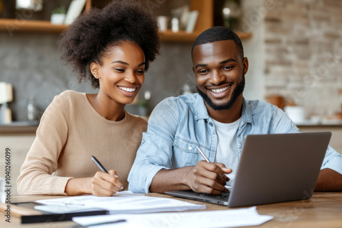 A man and woman, sitting together at a table with a laptop.