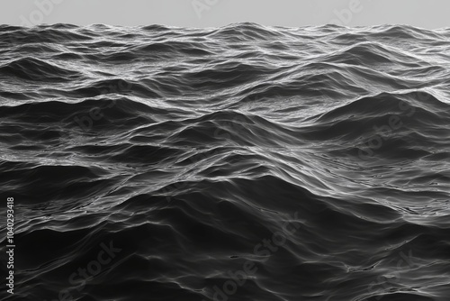 A dramatic black and white photo of the ocean waves, with the sun reflecting off of the water.