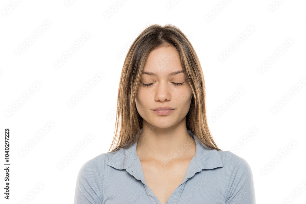 Portrait of a beautiful young serious woman without makeup and with closed eyes on a white studio background Portrait of a beautiful young serious woman without makeup and with closed eyes on a white studio background