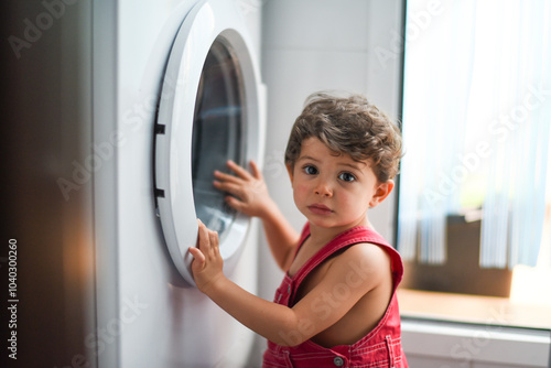 Little baby looking washing machine at home photo