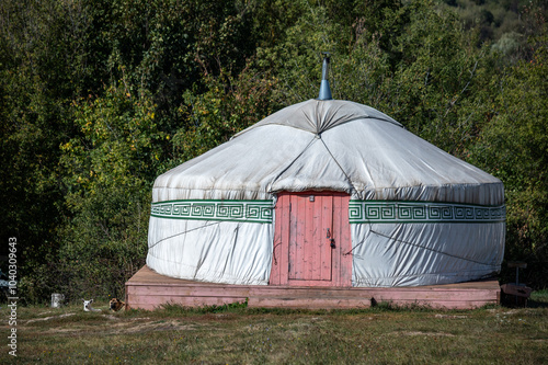 A white tent with a red door sits in a field