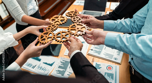 Group of multiracial business people joining gear wheels together over table as effective unity and productive teamwork concept. Efficient system business team process for solution solving. Meticulous