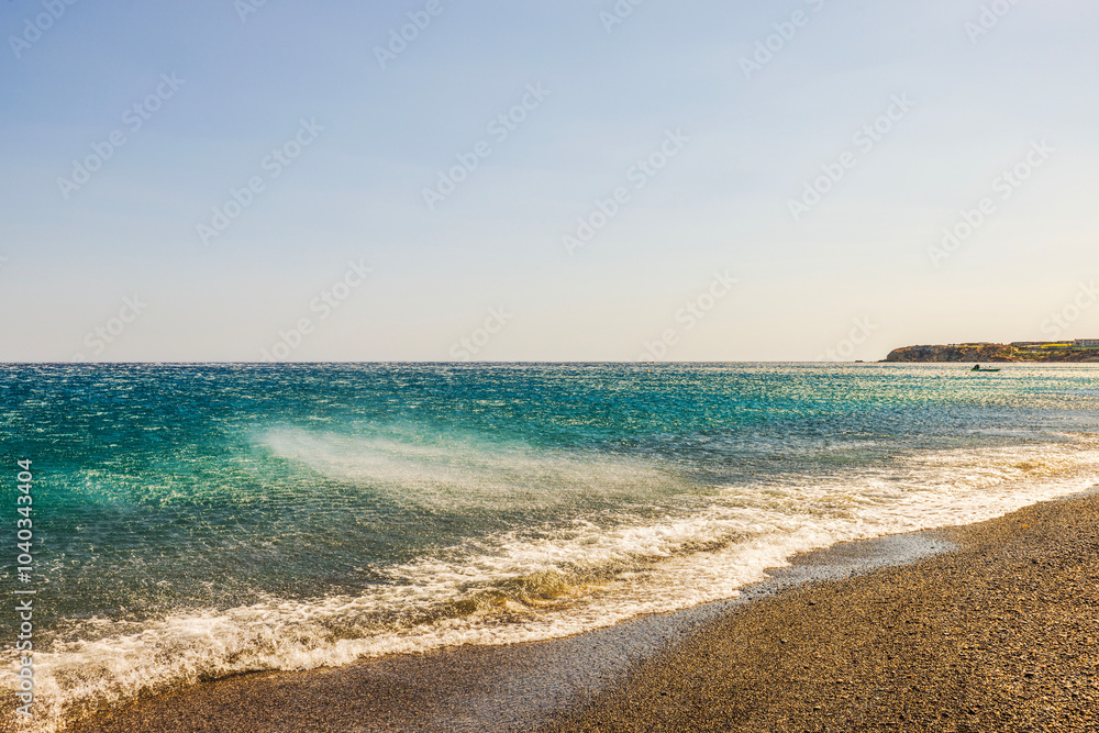 Waves of Mediterranean Sea being pushed away from the shore by strong winds coming down from mountains under clear sky. Greece. Waves of Mediterranean Sea being pushed away from the shore by strong winds coming down from mountains under clear sky. Greece.