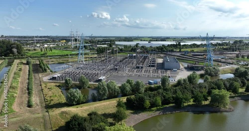 Drone view of a high voltage station surrounded by ponds and greenery, with a road in the background photo