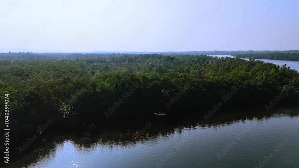 Little motor boat stands at the waterfront overgrown with thick lush forests. Drone footage rising above the waterscape in Sri Lanka. Little motor boat stands at the waterfront overgrown with thick lush forests. Drone footage rising above the waterscape in Sri Lanka.