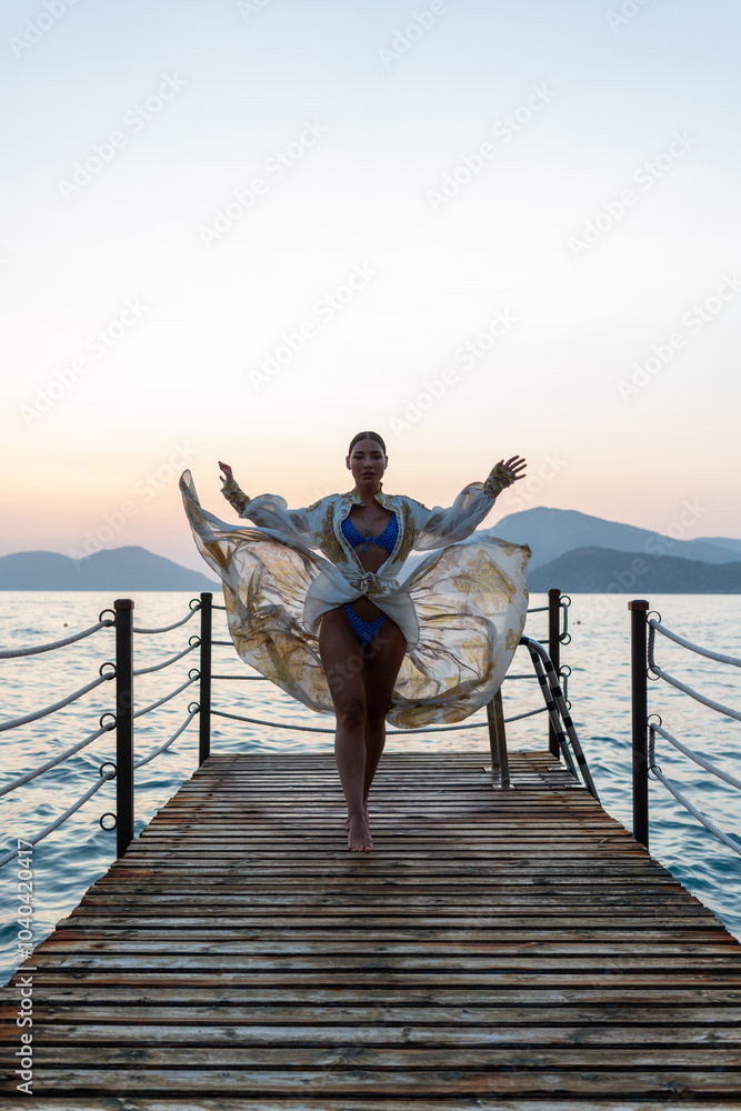 Fototapeta premium A stunning bikini model confidently posing on a pristine beach, showcasing the beauty of the coastline with a vibrant summer vibe. 
