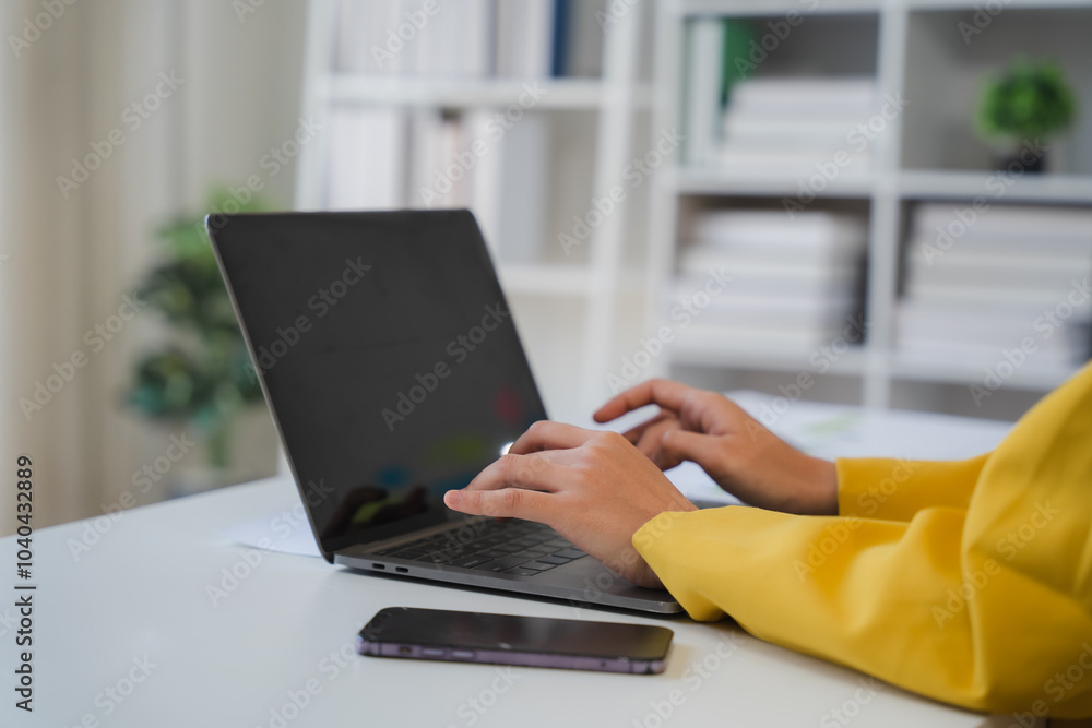 Fototapeta premium Focused Productivity: Hands typing on laptop in modern office