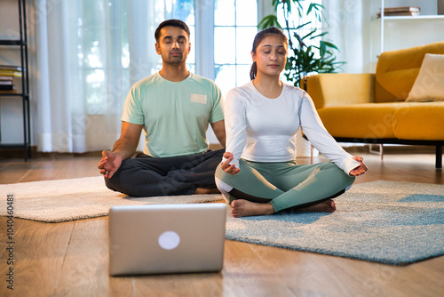 Indian Asian couple practicing pranayam and breathing exercises together, online yoga class at home photo