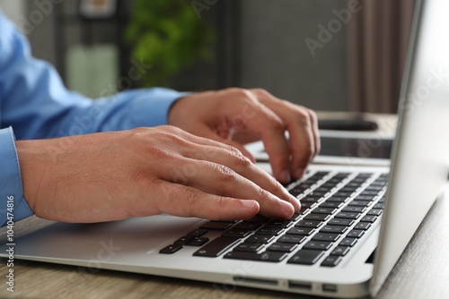 Businessman using laptop at wooden table, closeup. Modern technology