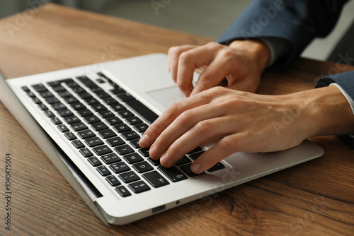 Businesswoman using laptop at wooden table indoors, closeup. Modern technology