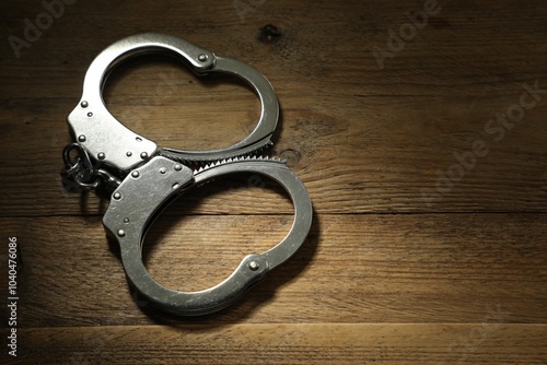 Classic chain handcuffs on wooden table, closeup. Space for text