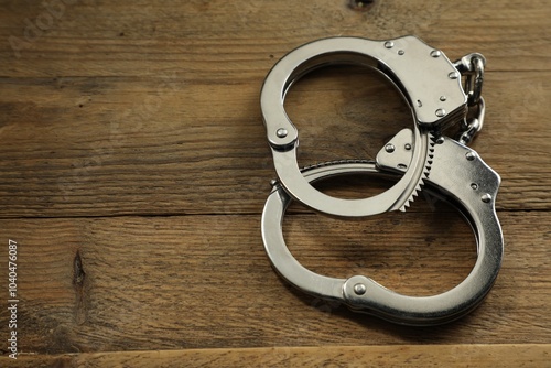 Classic chain handcuffs on wooden table, closeup. Space for text