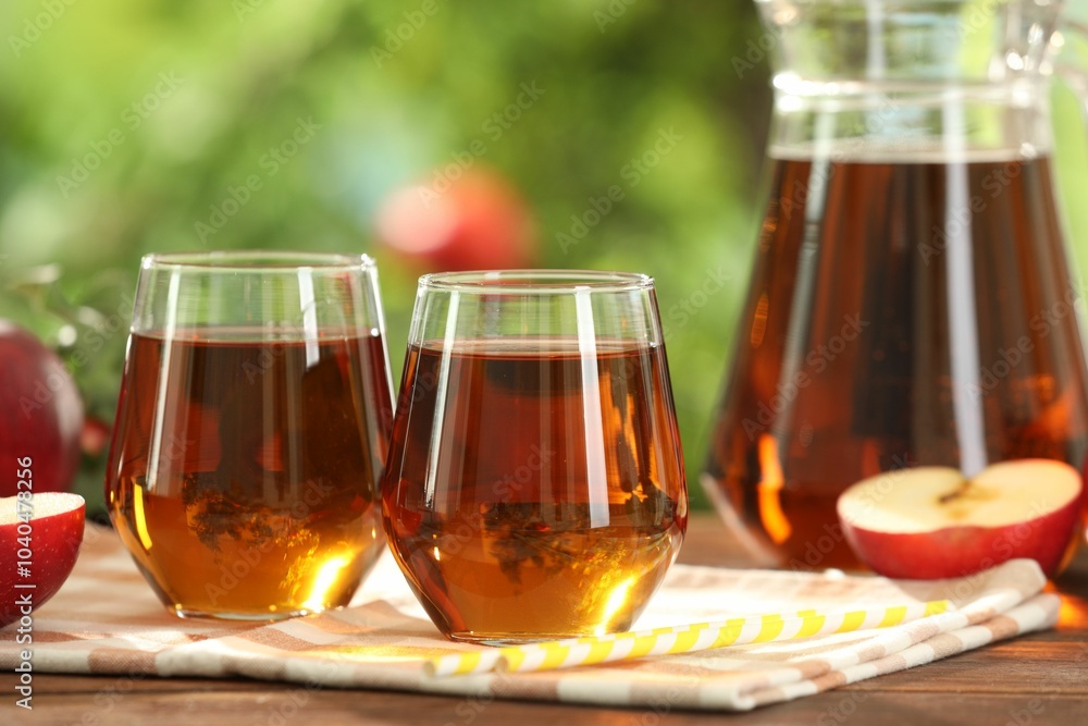 Tasty freshly made apple juice in glasses on wooden table outdoors Tasty freshly made apple juice in glasses on wooden table outdoors