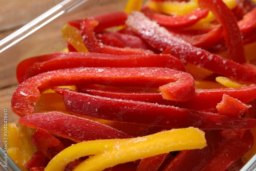 Slices of frozen bell peppers in glass container on table, closeup Slices of frozen bell peppers in glass container on table, closeup