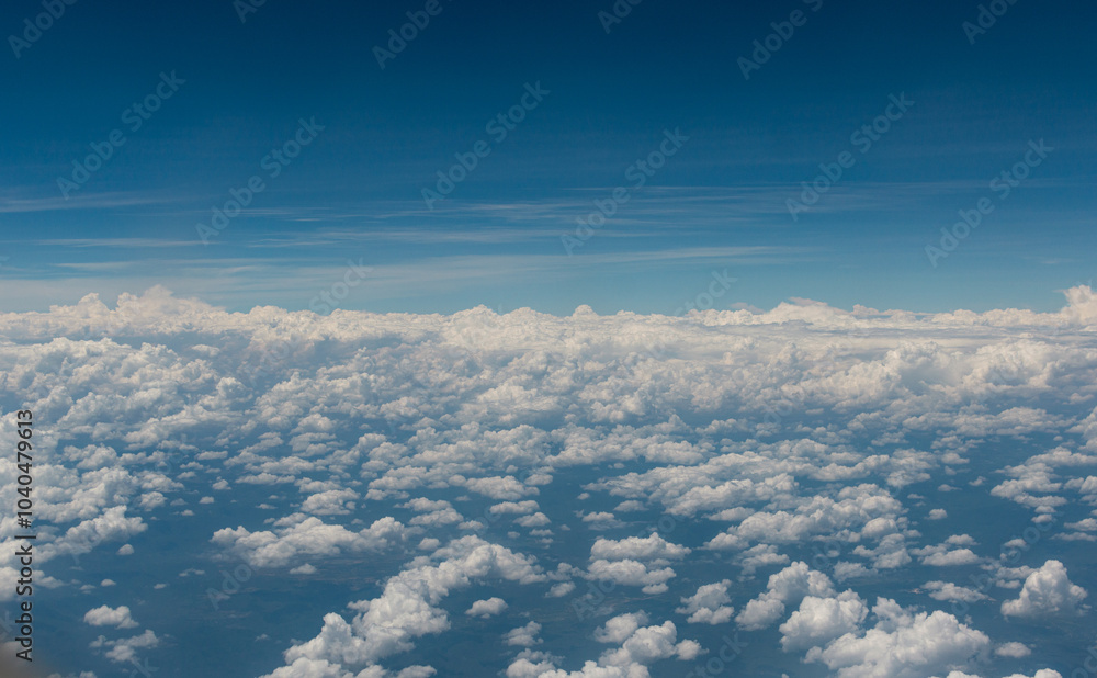 Paisaje de cielo con nubes arreboladas se extiende bajo un cielo azul profundo, visto desde un avión