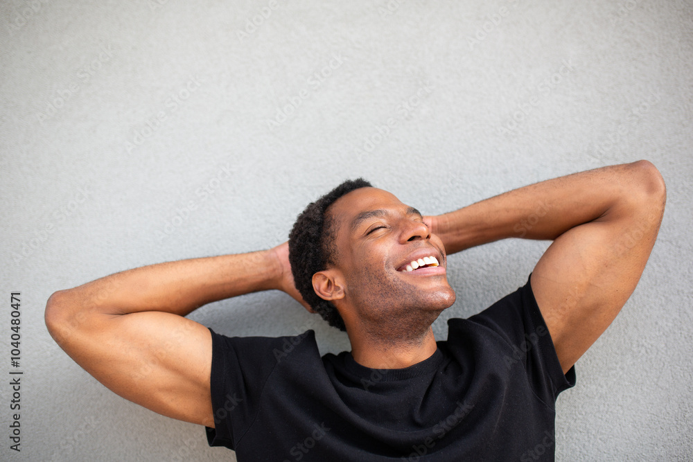 Man smiling and relaxing with hands behind head on gray background Man smiling and relaxing with hands behind head on gray background