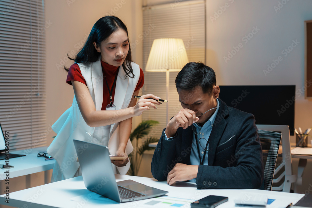 Businesswoman holding pen pointing at paperwork while businessman taking off eyeglasses rubbing his nose bridge Businesswoman holding pen pointing at paperwork while businessman taking off eyeglasses rubbing his nose bridge