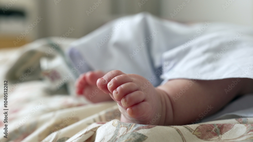 Fototapeta premium Close-up of a baby’s tiny foot resting on a patterned bedspread. the delicate details of babyhood in a cozy, indoor environment