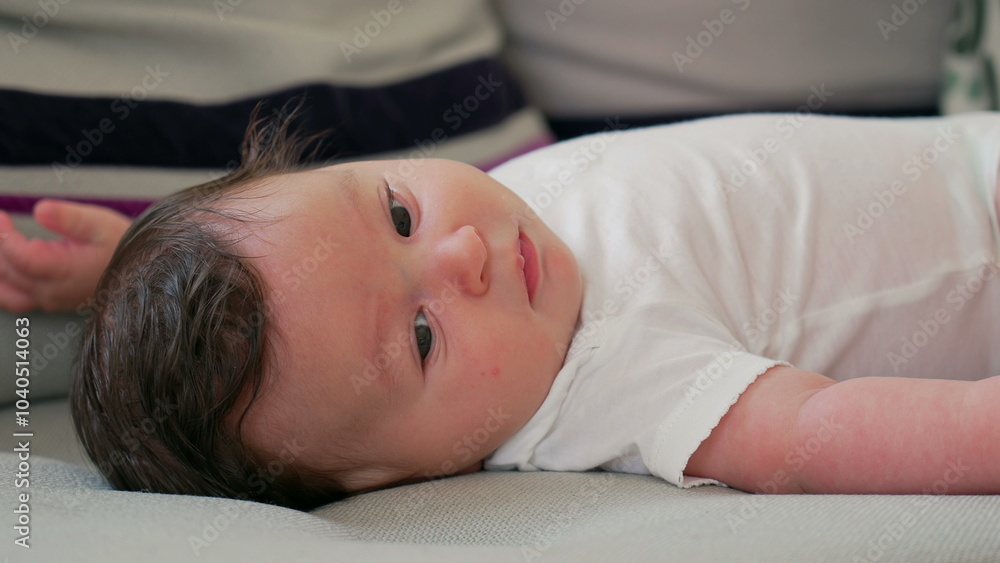 Close-up of baby lying on a couch, gazing attentively while relaxing indoors in a comfortable and cozy home environment Close-up of baby lying on a couch, gazing attentively while relaxing indoors in a comfortable and cozy home environment
