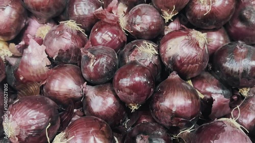 Close-up footage of pile of red onions on a shelf of a supermarket