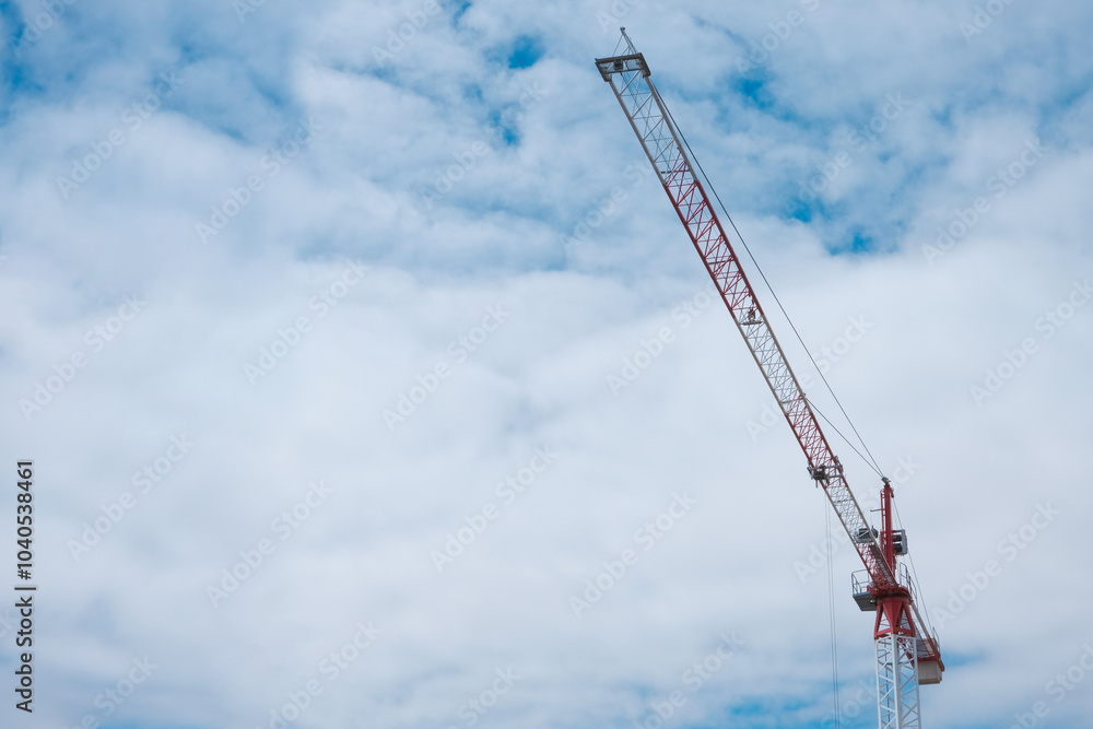 The crane works against the blue sky. Construction, investment, real estate sales. Space for text. The crane works against the blue sky. Construction, investment, real estate sales. Space for text.